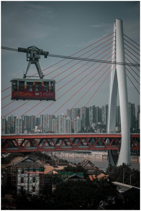 A cable car gracefully passes over a modern bridge