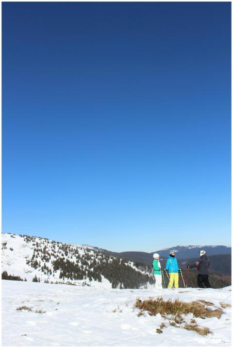 Three skiers standing on a snowy mountain under a