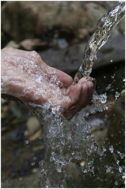 Close-up of a human hand under a stream of clear,