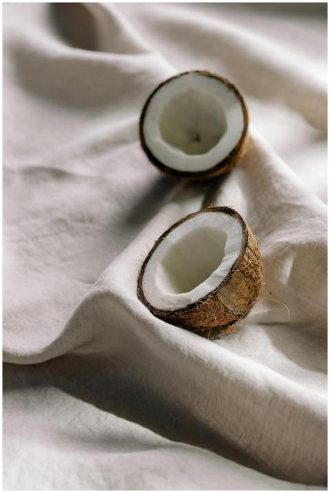 Coconut halves resting on soft white cloth, showca