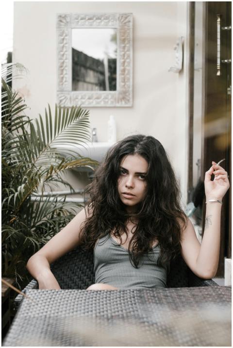 A thoughtful young woman with long hair sits outdo