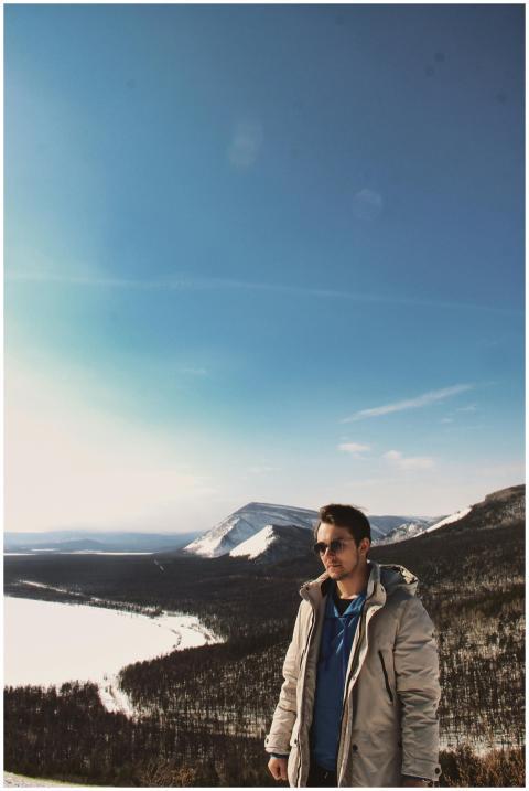 A man stands overlooking a snowy mountain landscap