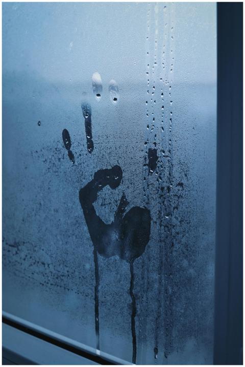 Eerie handprint on a moisture-covered window, evok