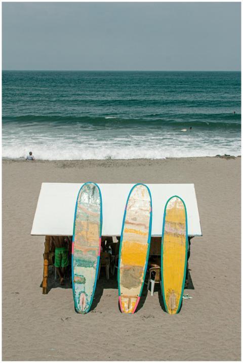 Three surfboards leaning against a beach shed by t
