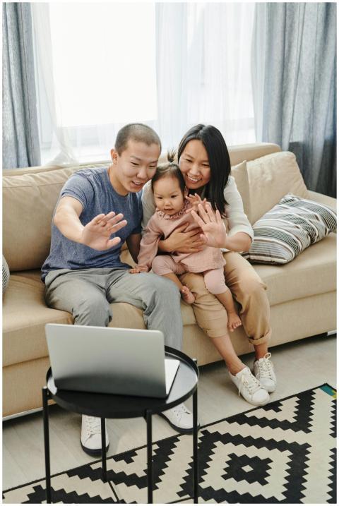 Smiling family waving at laptop during video chat