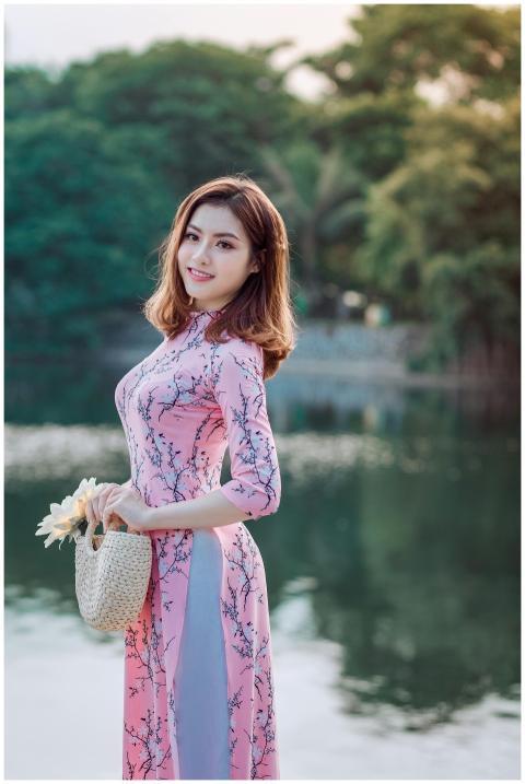 A smiling woman poses gracefully in a pink dress b