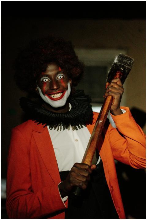 A sinister clown grins eerily, holding a hammer, i