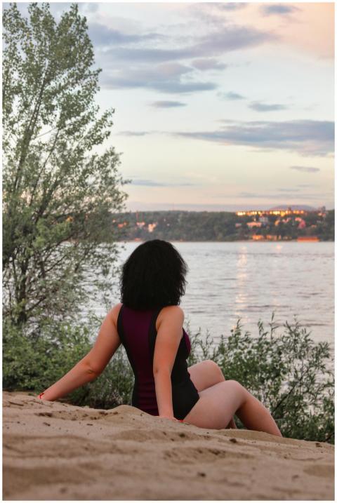 A woman in a swimsuit enjoys a peaceful sunset by