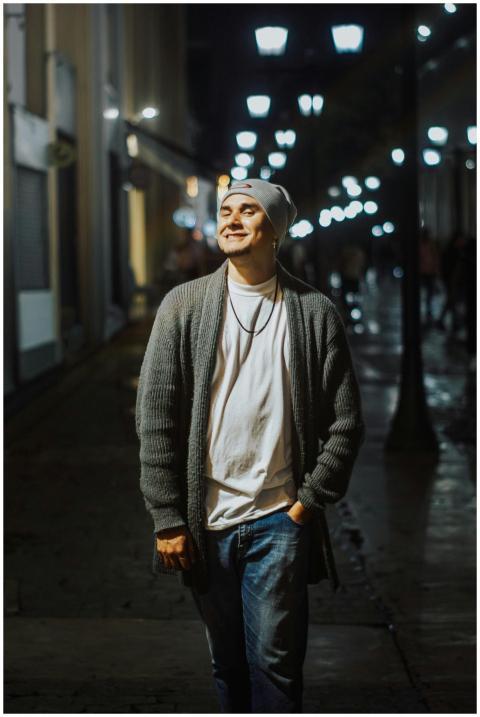 A young man walks confidently down a well-lit stre