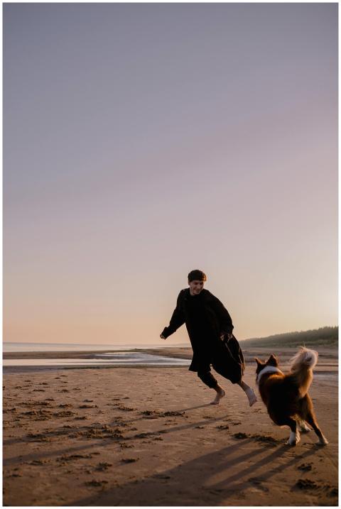 A man joyfully runs barefoot on the beach with his