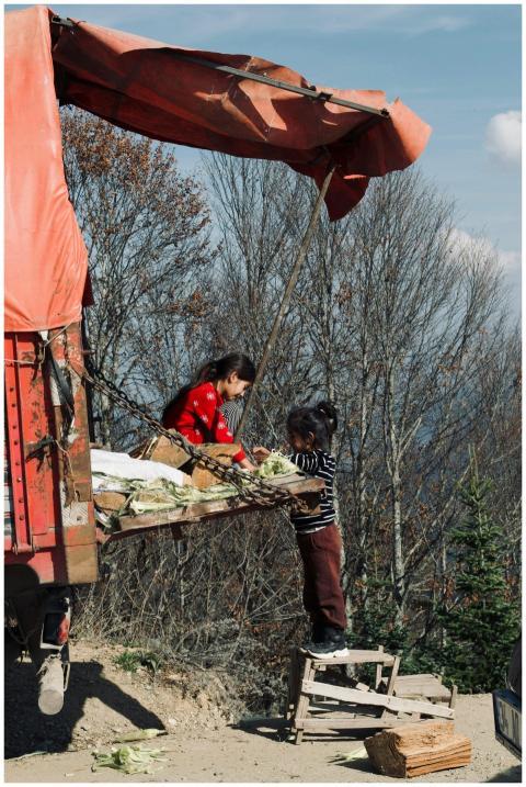 Two young girls sorting corn on a truck in a rural