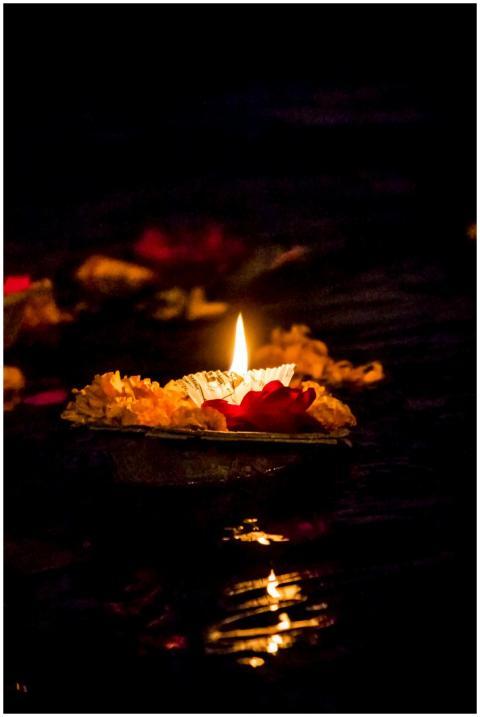 A close-up of a candle with flowers on water durin