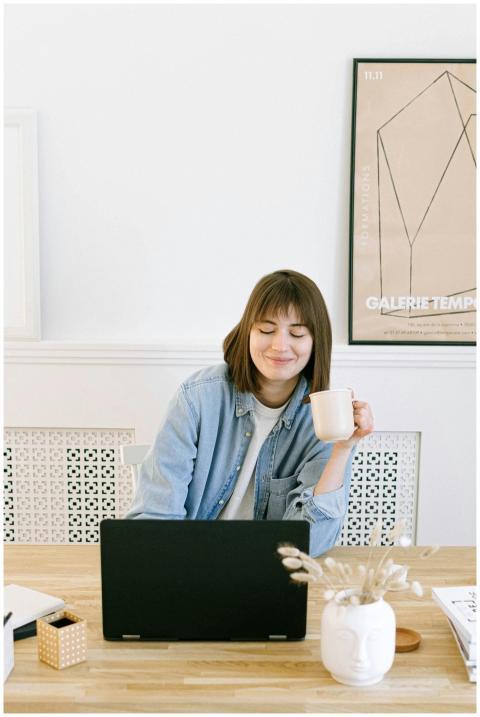 Woman in a home office setting, smiling with a cof