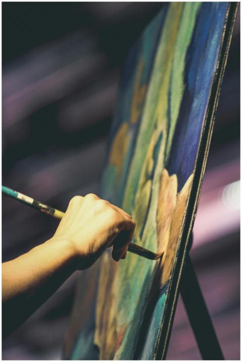An artist's hand painting a vibrant abstract artwo