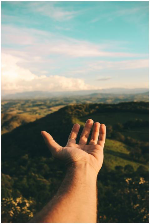 A hand reaching out towards a scenic view of mount