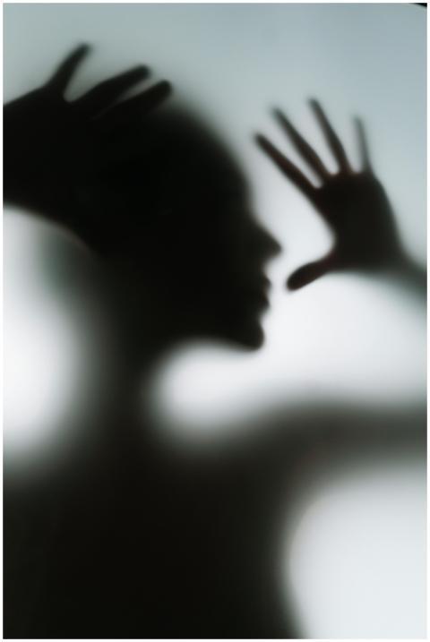 Silhouette of a human figure behind frosted glass