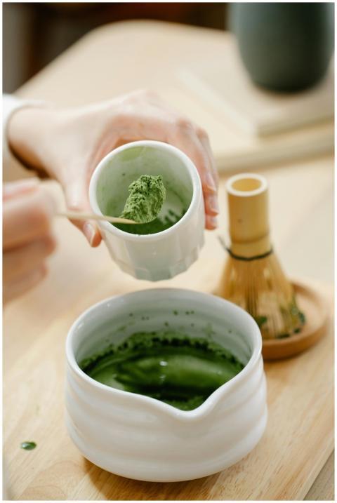 Close-up of hand preparing matcha tea with traditi