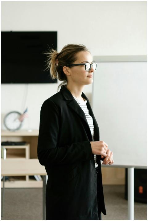 A confident woman wearing a black blazer and glass
