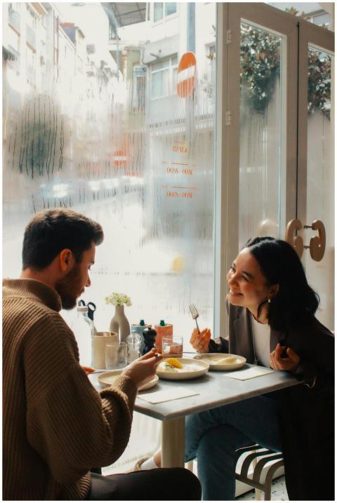 Two adults enjoying a meal in a cozy cafe, laughin
