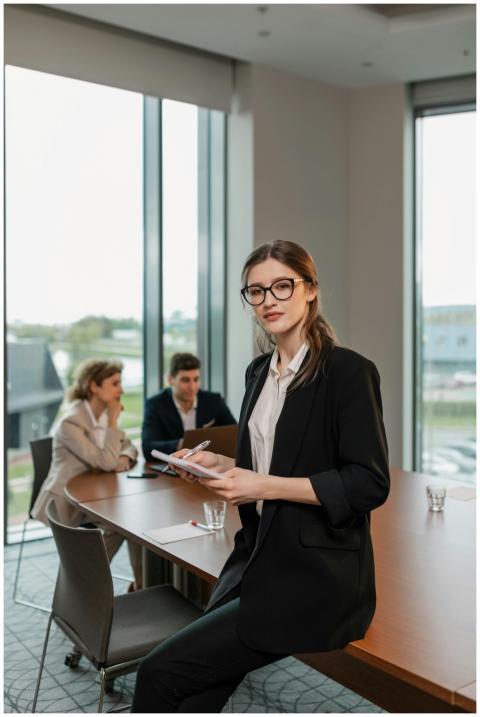 Professional woman in a black blazer holding a not