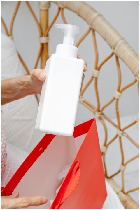 Close-up of a hand holding a white bottle with a p