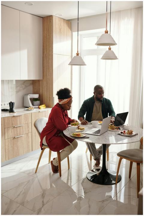 A couple enjoys breakfast while using laptops in a