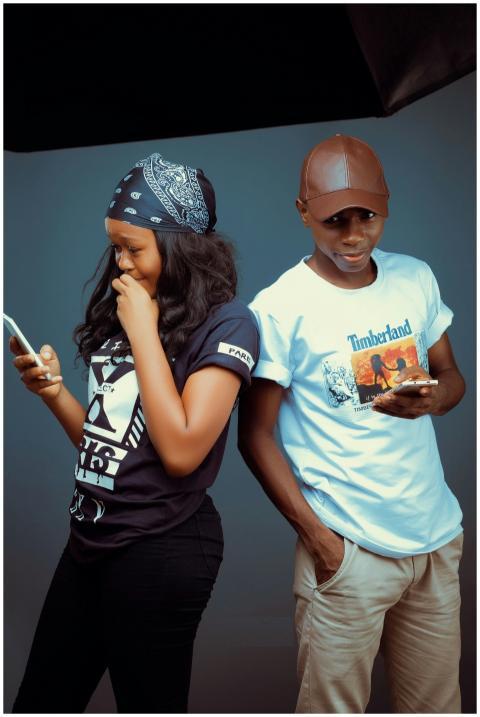 Teenage siblings in casual fashion texting on smar