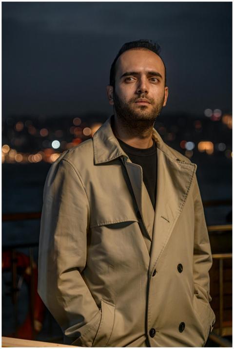 Portrait of a man in a beige trench coat with city