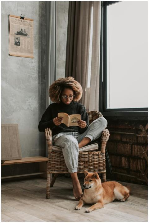 Young woman with afro hair reading a book by the w