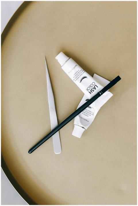 Stylish flat lay of eyelash tint and tools on a be