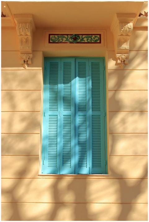 Artistic image of blue window shutters on a beige