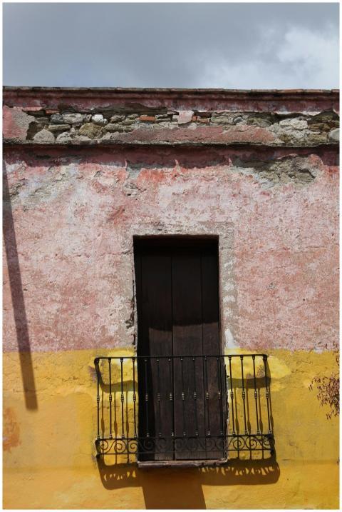 A rustic balcony against a vibrant pink and yellow