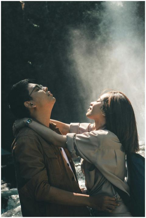 A young couple lovingly embraces under a waterfall