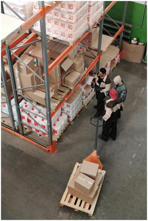 Three warehouse workers discussing inventory organ