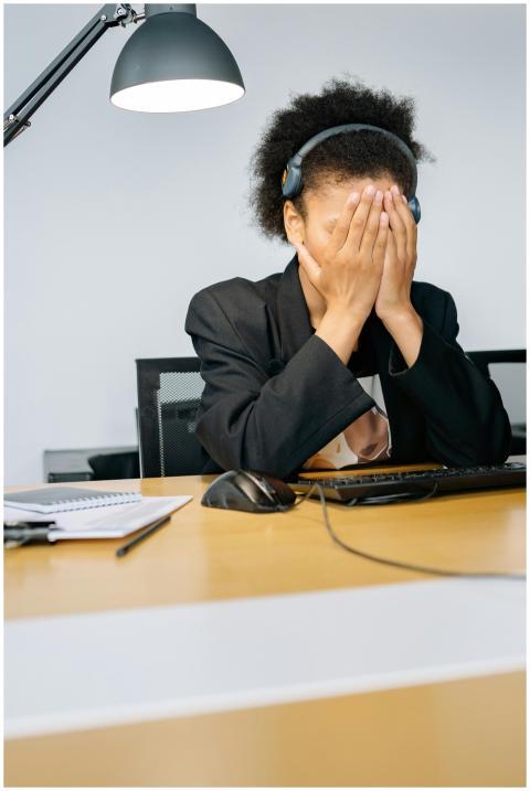 A tired call center employee covering her face wit