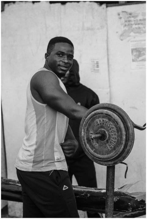 A man lifting weights at an outdoor gym, showcasin