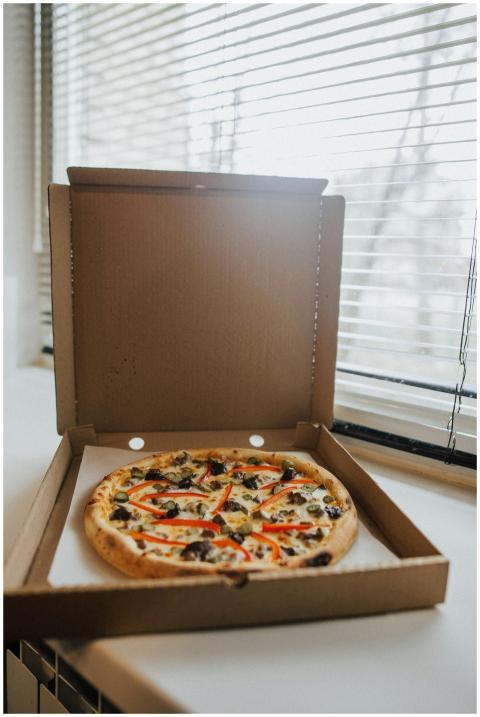 Tasty pepperoni pizza in an open box by a window,