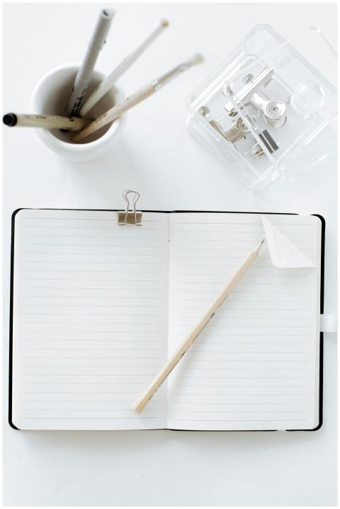 Top view of an open notebook with pen, pencils, an