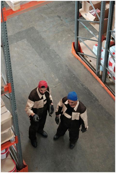 Two workers in a warehouse discussing logistics in