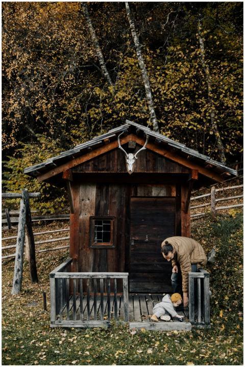 A father and child play together outside a rustic