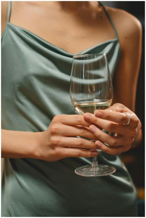 Close-up of a woman in a silk dress holding a wine