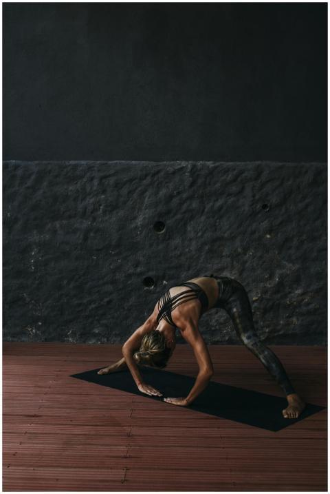 Female practicing yoga pose indoors on mat in dim