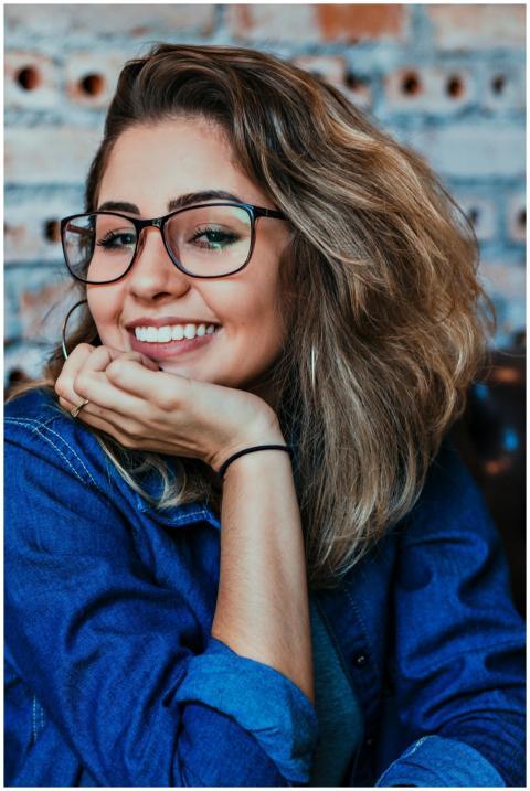 A young woman wearing glasses and denim, smiling i