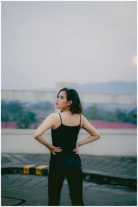 A brunette woman in black attire poses confidently