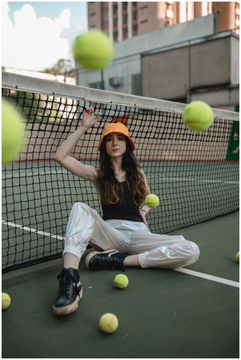 Woman in stylish attire with tennis balls on an ur