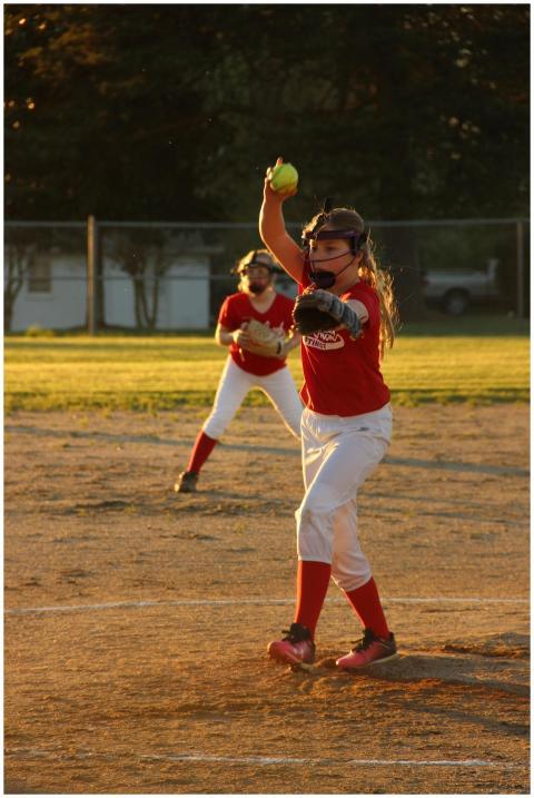 Young girls play softball outdoors during golden h