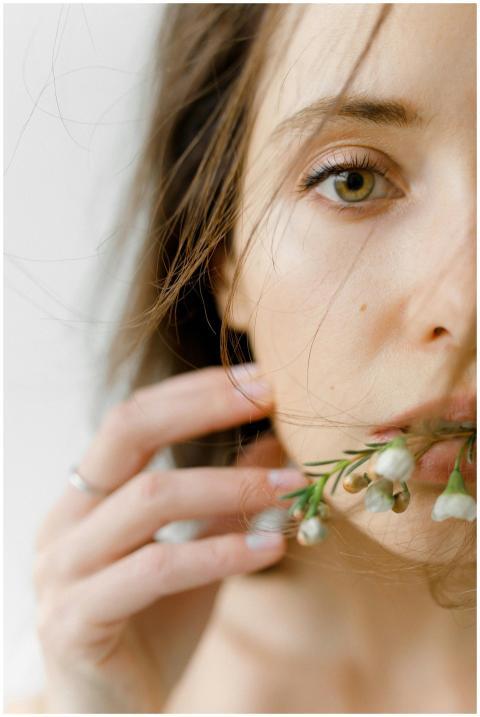 Close-up of a woman with flowers near her face, sh