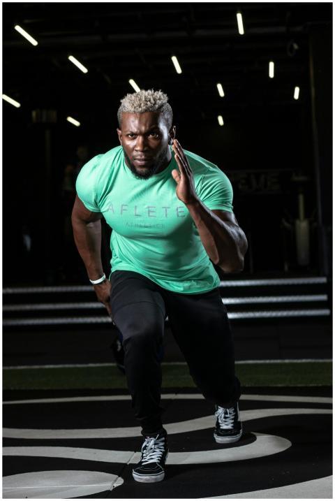 Athletic man in green shirt sprinting indoors, sho