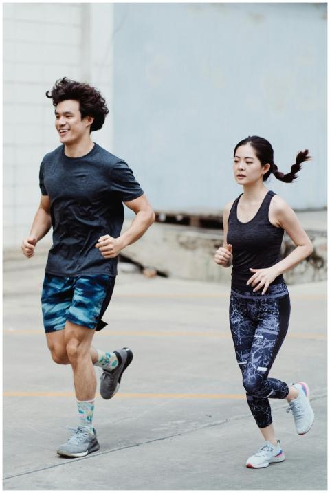 Asian couple jogging together outdoors, promoting