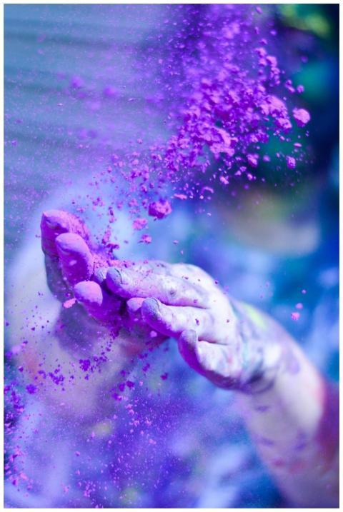 Close-up of hands throwing vibrant purple powder o